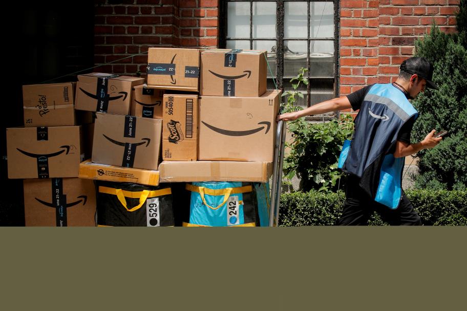 An Amazon delivery worker pulls a delivery cart full of packages during its annual Prime Day promotion in New York City, U.S., June 21, 2021.  REUTERS/Brendan McDermid/File Photo