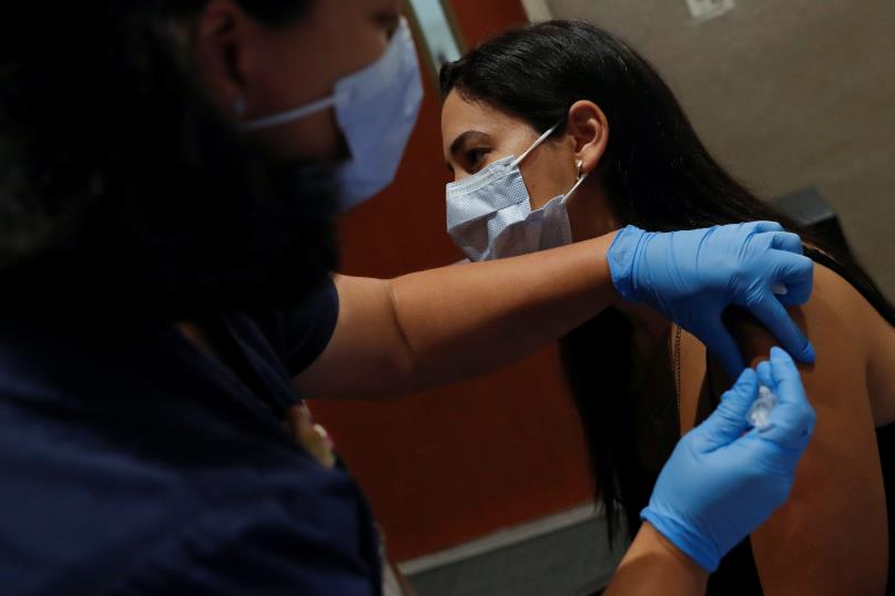 A registered nurse applies a dose of the Moderna COVID-19 vaccine to Sarasota Hospital patient technician Carol Garcia at the Sarasota Memorial Hospital in Sarasota, Florida, U.S., September 24, 2021. REUTERS/Shannon Stapleton