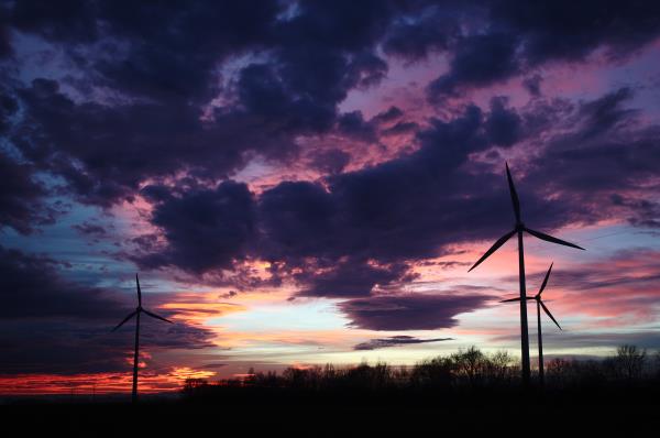 The setting sun illuminates the sky behind turbines of a wind park near Neusiedl am See