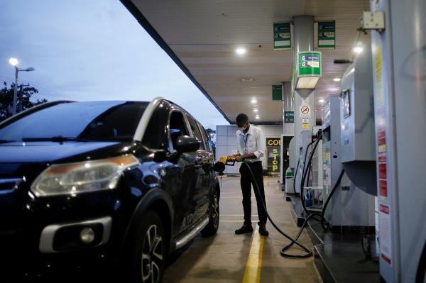 A worker uses a petrol pump at a Brazilian oil company Petrobras gas station in Brasilia