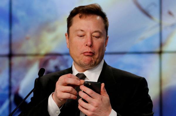 Elon Musk looks at his mobile phone during a post-launch news co<em></em>nference to discuss the  SpaceX Crew Dragon astro<em></em>naut capsule in-flight abort test at the Kennedy Space Center