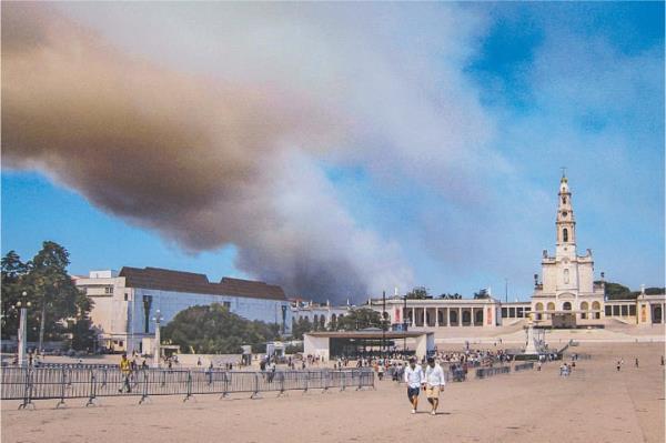 A COLUMN of smoke billows above the Sanctuary of Our Lady of Fatima, after a wildfire broke out on Saturday. The fire reached the town as around 200,000 pilgrims flooded the shrine in Portugal to attend a service held by Pope Francis at one of Catholicism’s most revered sites.—AFP