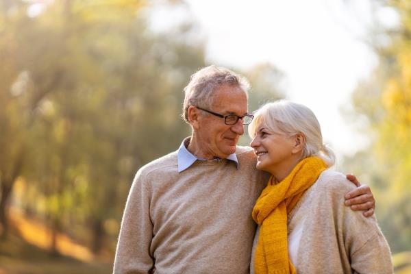 senior couple looking at each other and hugging while outside among trees