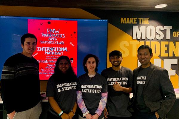 Five people stand together in "Mathematics and Statistics" t-shirts