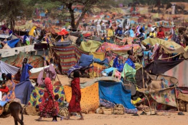 A jumble of tents improvised from cloths and sticks in a desert-like landscape