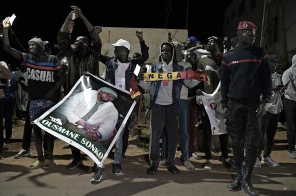 People celebrate the release of Senegalese opposition leader Ousmane So<em></em>nko and ally Bassirou Diomaye Faye. They are holding pictures of the men, and a banner reading SENEGAL. They look happy.