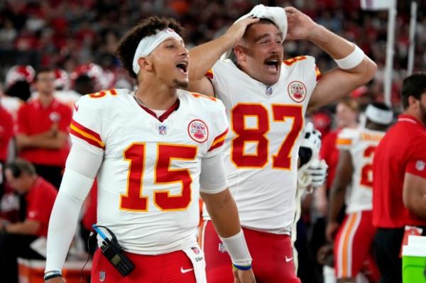 Kansas City Chiefs quarterback Patrick Mahomes (15) and tight end Travis Kelce (87) cheer from the sidelines during the first half of an NFL preseason football game against the Arizona Cardinals, Saturday, Aug. 19, 2023, in Glendale, Ariz. (AP Photo/Rick Scuteri)