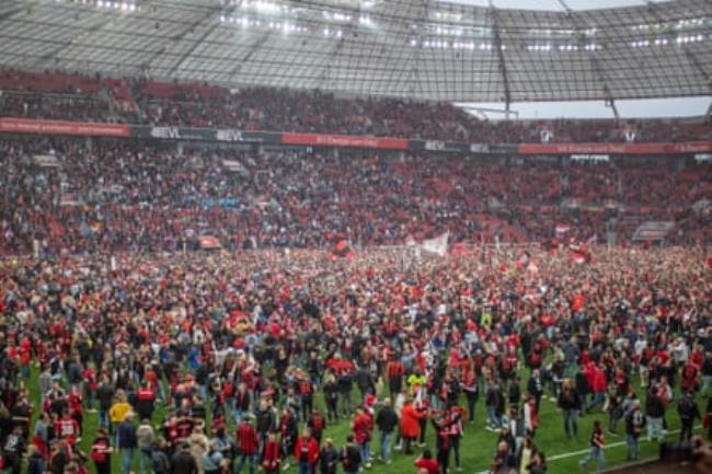 Fans celebrate on the pitch after Leverkusen’s title victory.