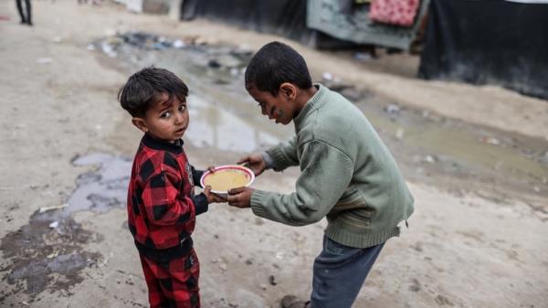 Palestinian children receive food supplies from charity organisations in Deir al-Balah, Gaza