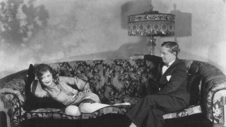 Clara Bow relaxes on the sofa of her Beverly Hills home, in the company of her father, Robert Bow, in 1928.