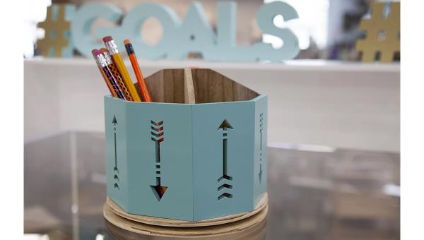 A teal wooden pen holder with pencils in it. 