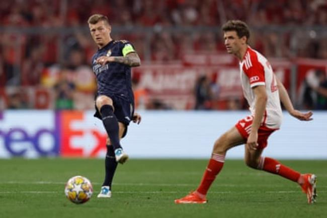 Toni Kroos plays a pass as Thomas Müller watches on