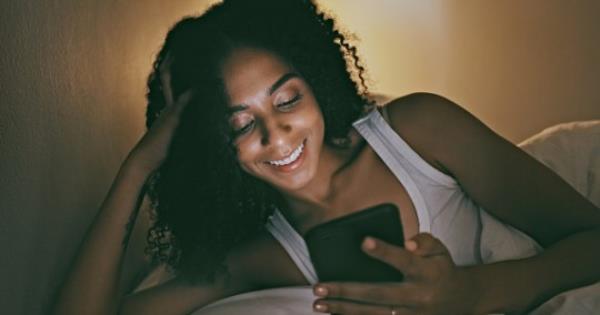 Night, black woman and smartphone for social media, communication and texting while in bed, smile or chatting. Dark, African American female or lady in bedroom with cellphone to search or read online