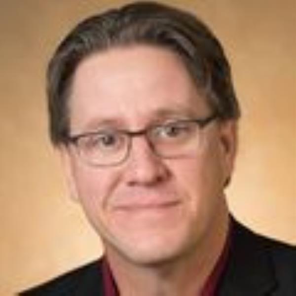 Larry Sherman, Ph.D., has short brown hair, eye glasses and a black shirt, he is smiling against an orange/brown background.