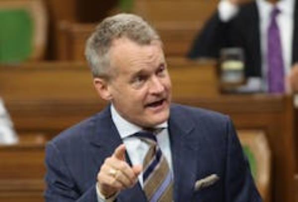 A middle-aged white man with blo<em></em>nde hair points his index finger while speaking to someone off-camera