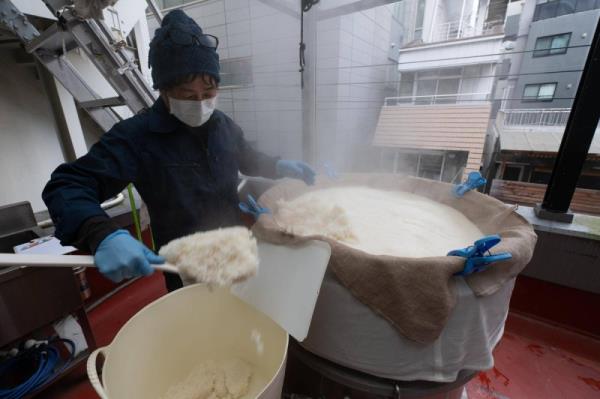 Sake production in the heart of Tokyo: Master Brewer Yoshimi Terasawa transfers rice, sake's key ingredient, from a vat on the brewery's fourth-floor balcony.