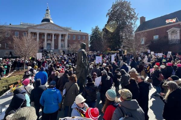 A protester wearing a Grateful Dead shirt saying Make America Grateful Again carries a sign. Protesters rally on President's Day at Lawyers Mall in Annapolis against the policies of President Do<em></em>nald Trump and Elon Musk as part of the natio<em></em>nwide "50501" Movement. (Paul W. Gillespie/Staff)