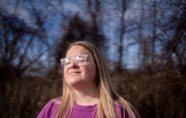 A woman closes her eyes as she stand in the sun